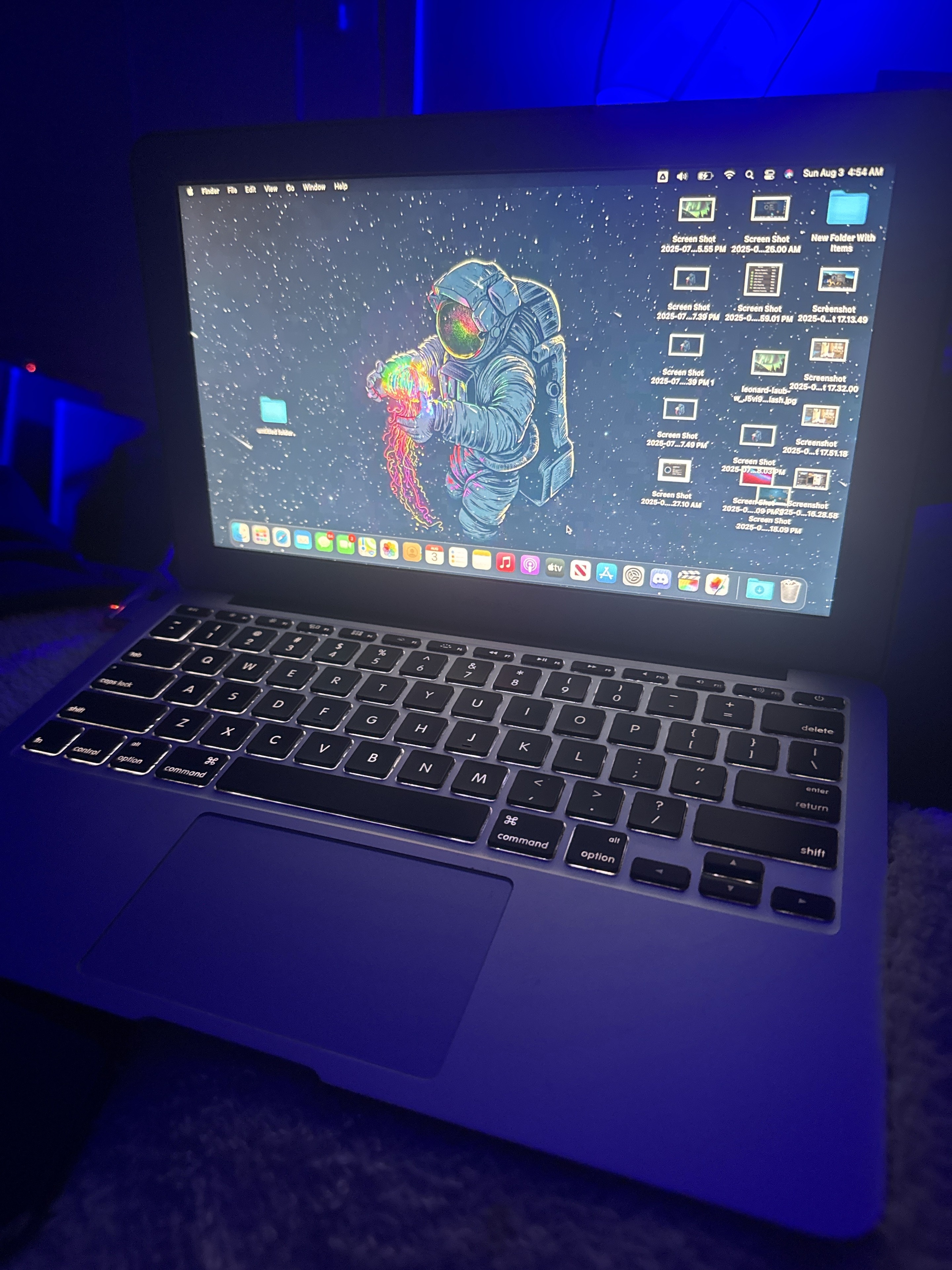 MacBook with an astronaut wallpaper under blue lighting
